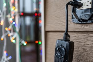 A Christmas lights timer plugged into an outdoor GFCI outlet, demonstrating safe and convenient holiday lighting.