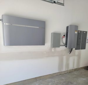 Solar battery system installed in garage with wall-mounted energy storage units and electrical disconnects in Great Falls home